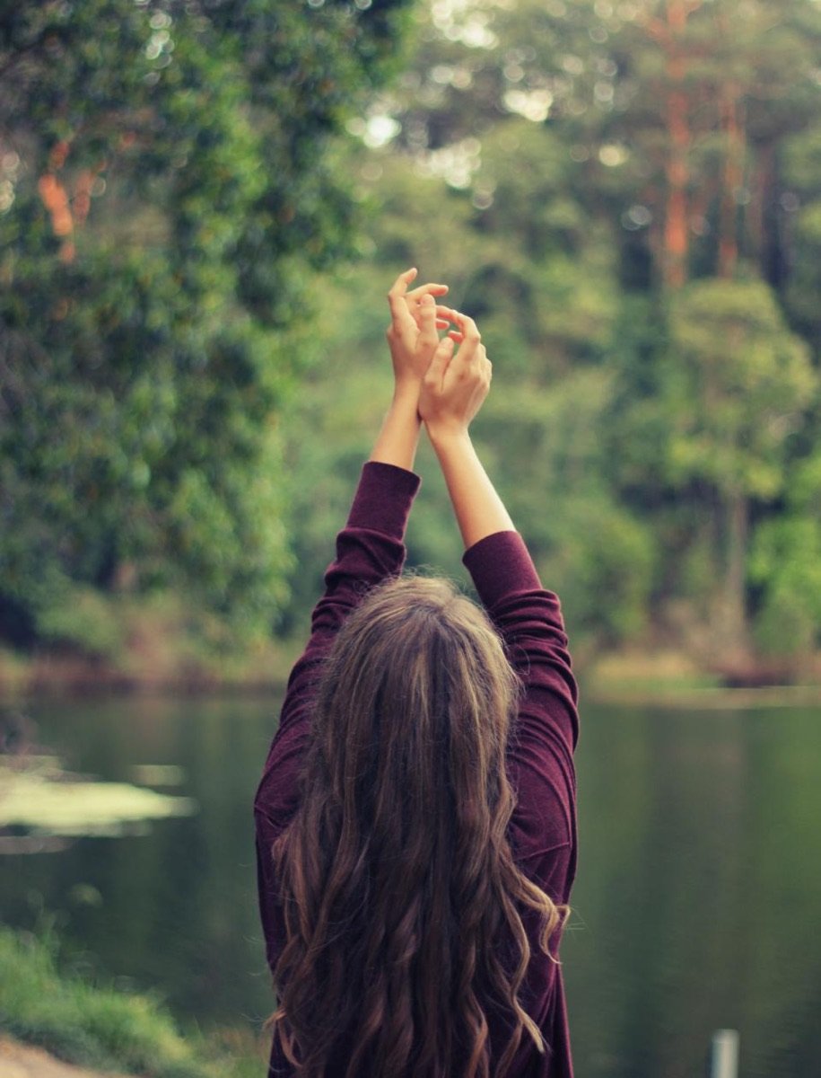Mujer estirando con los brazos arriba al aire libre