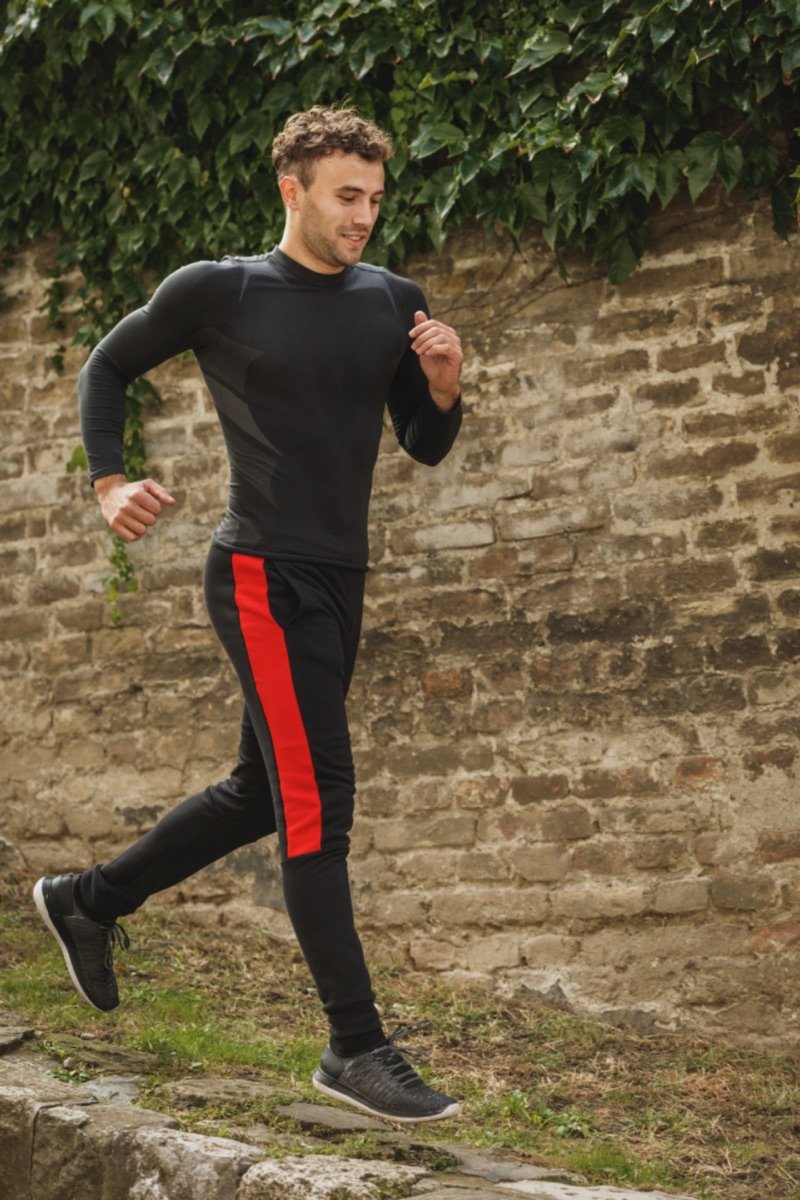 Hombre corriendo junto a una pared de ladrillo