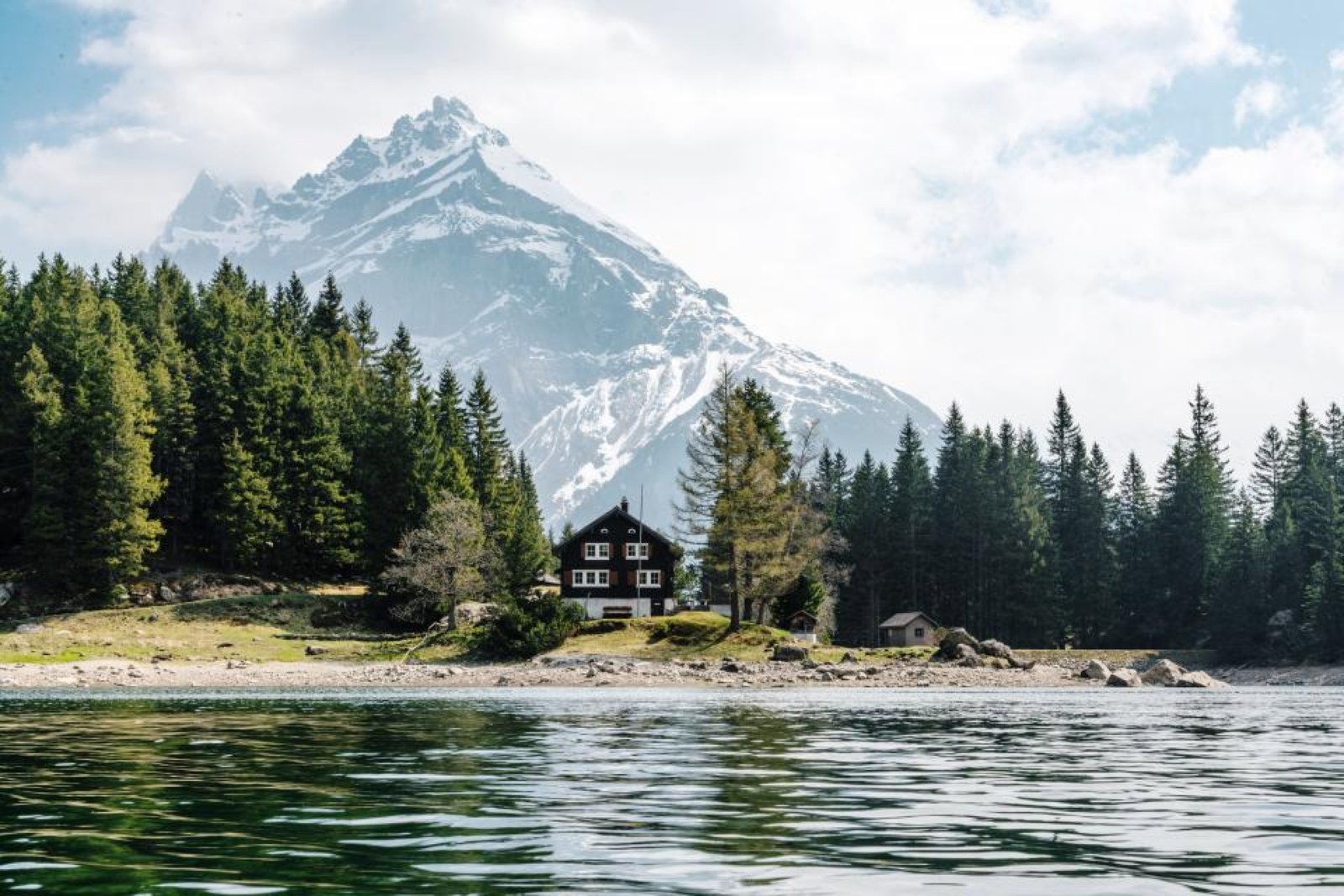 Casa de madera junto a un lago con montañas