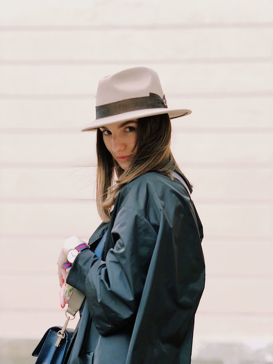 Mujer con sombrero y abrigo sobre fondo claro