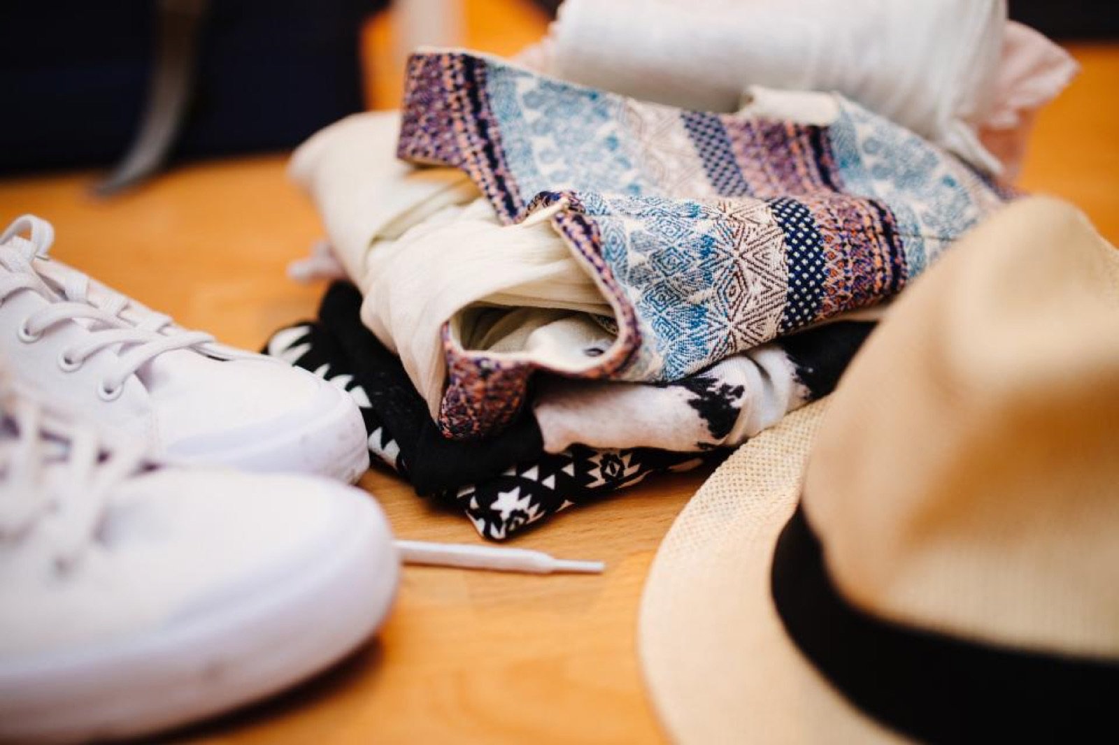 Zapatillas blancas junto a prendas dobladas