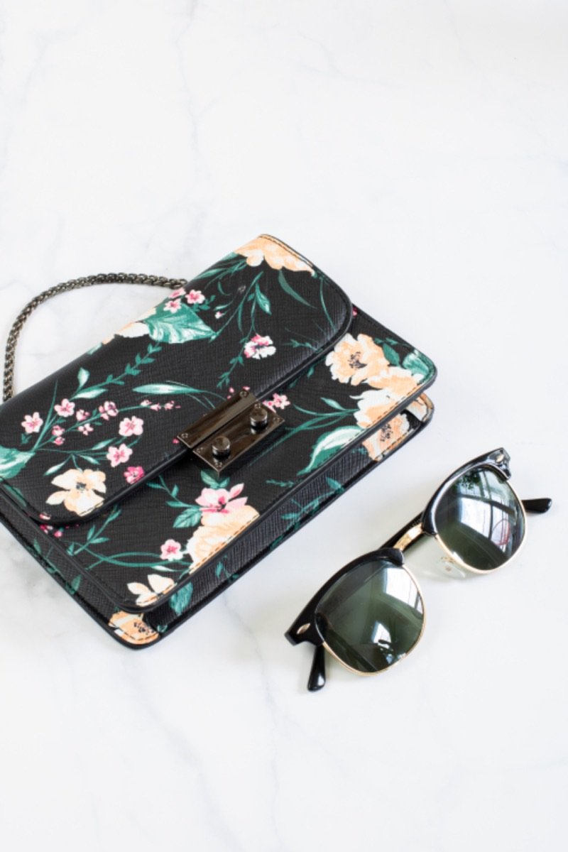 Cartera estampada con flores junto a anteojos