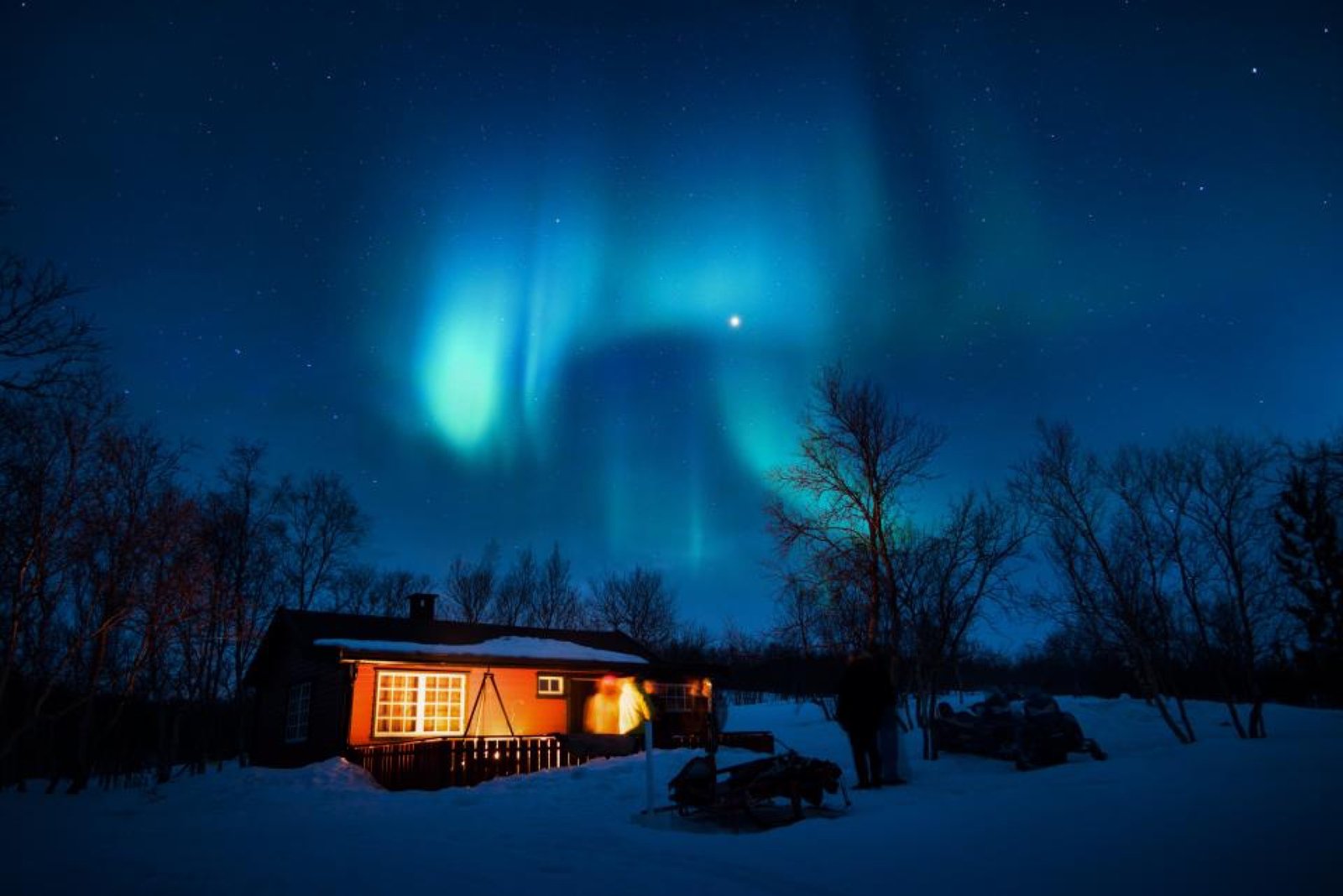 Aurora boreal verde sobre una cabaña